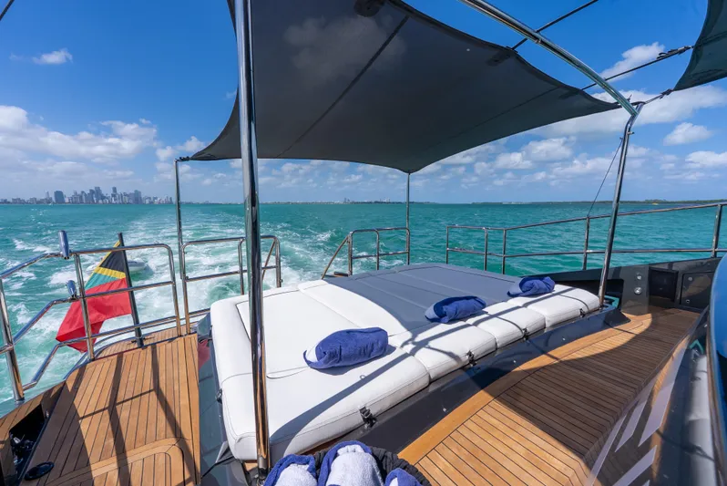  Yacht Photos Pics Luxurious Palmer Johnson 120 yacht deck with sunbeds, ocean view, and city skyline in the background.