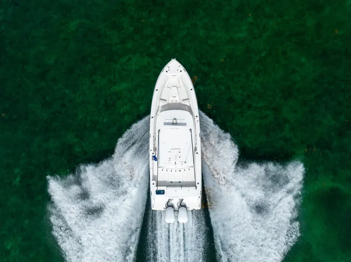 Yacht Photos Pics Aerial view of 2019 Everglades 335 Center Console boat cruising on clear green water.