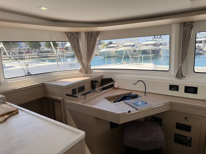 Gemini Yacht Photos Pics Interior of 2024 Lagoon 46 yacht with modern navigation station and marina view.