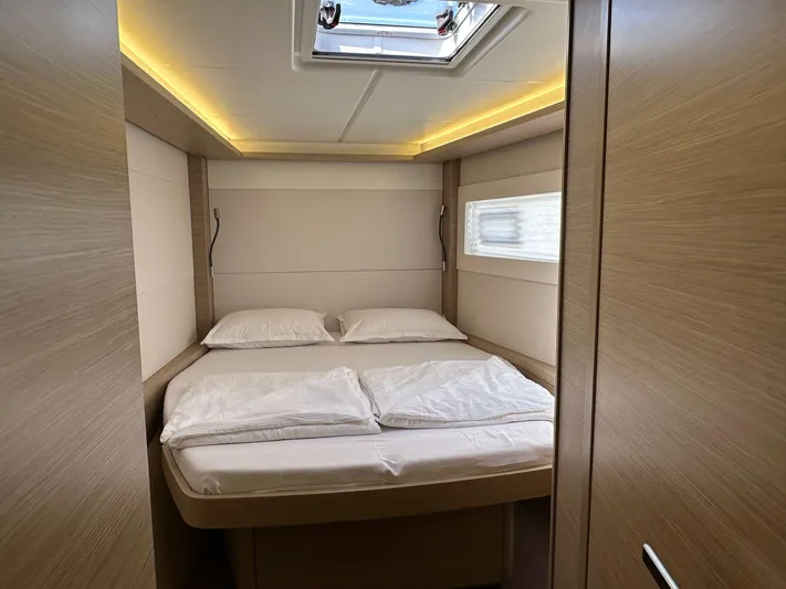 Gemini Yacht Photos Pics 2024 Lagoon 46 yacht cabin with cozy bed, modern lighting, and wooden interior.