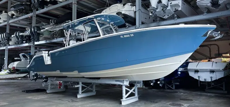  Yacht Photos Pics 2018 Cobia 344 Center Console boat in storage, blue hull, elevated on stands.
