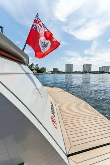Incentivized Yacht Photos Pics Vanquish VQ58 yacht docked by the water, featuring a red flag, 2021 model.