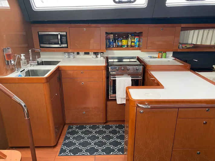 Blue Pearl Yacht Photos Pics Interior of 2016 Beneteau Oceanis 60 yacht kitchen with wooden cabinetry and modern appliances.