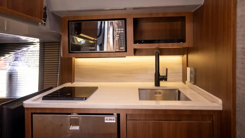  Yacht Photos Pics Modern RV kitchen with microwave, sink, and stovetop in Hanover 447, 2025 model.