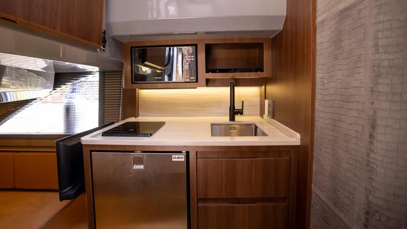  Yacht Photos Pics Compact modern kitchen in 2025 Hanover 447 RV with wood cabinetry and stainless steel appliances.