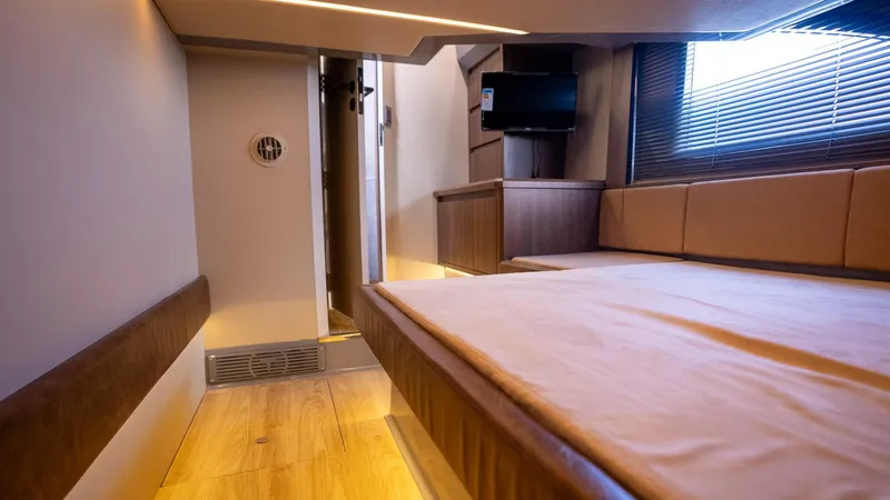  Yacht Photos Pics Modern interior of Hanover 447 yacht, featuring cozy bed, TV, and wooden accents, 2025 model.