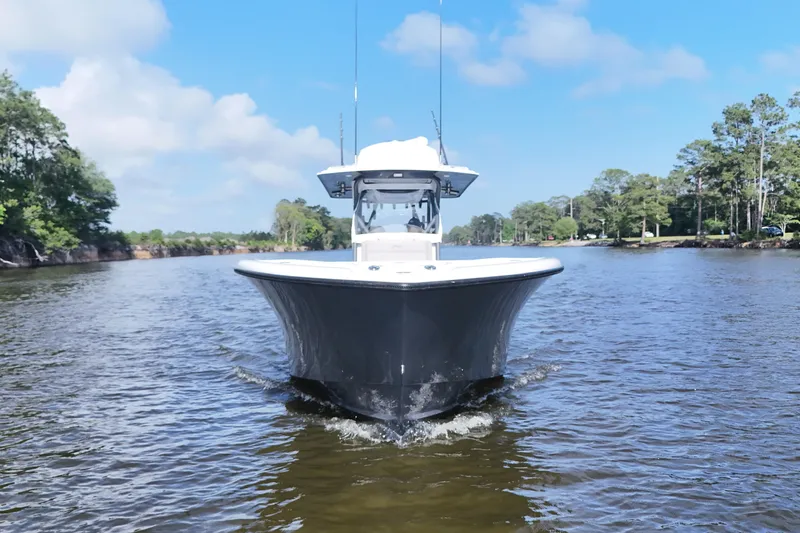 Warranty X Trailer Yacht Photos Pics 2022 Yellowfin 34 Offshore boat cruising on a scenic river under a clear blue sky.