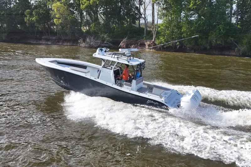 Warranty X Trailer Yacht Photos Pics 2022 Yellowfin 34 Offshore boat cruising on a river with lush green trees.