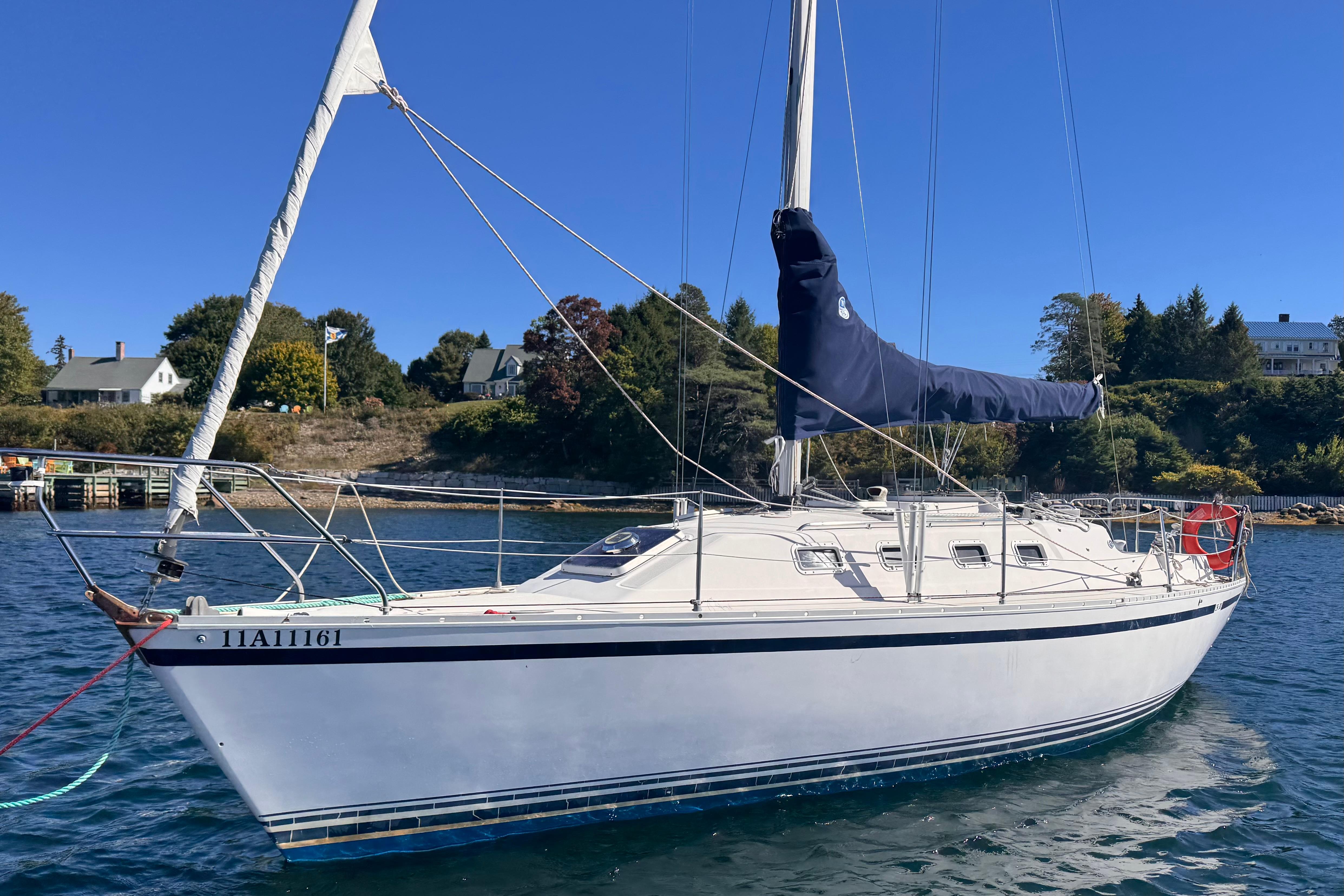 1986 CS 30 sailboat anchored in calm waters, with scenic shoreline background.