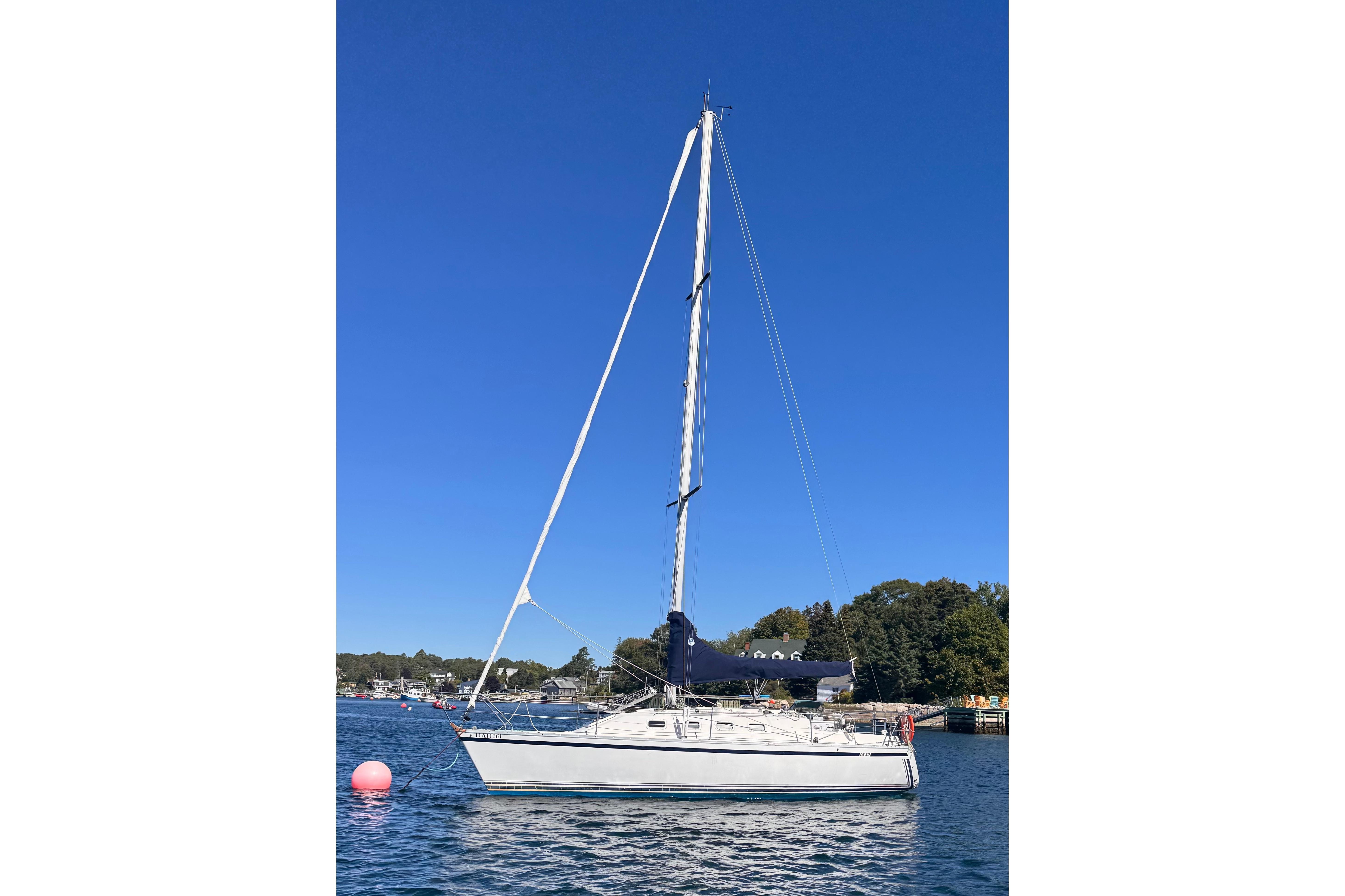 1986 CS 30 sailboat on calm water with clear blue sky background.