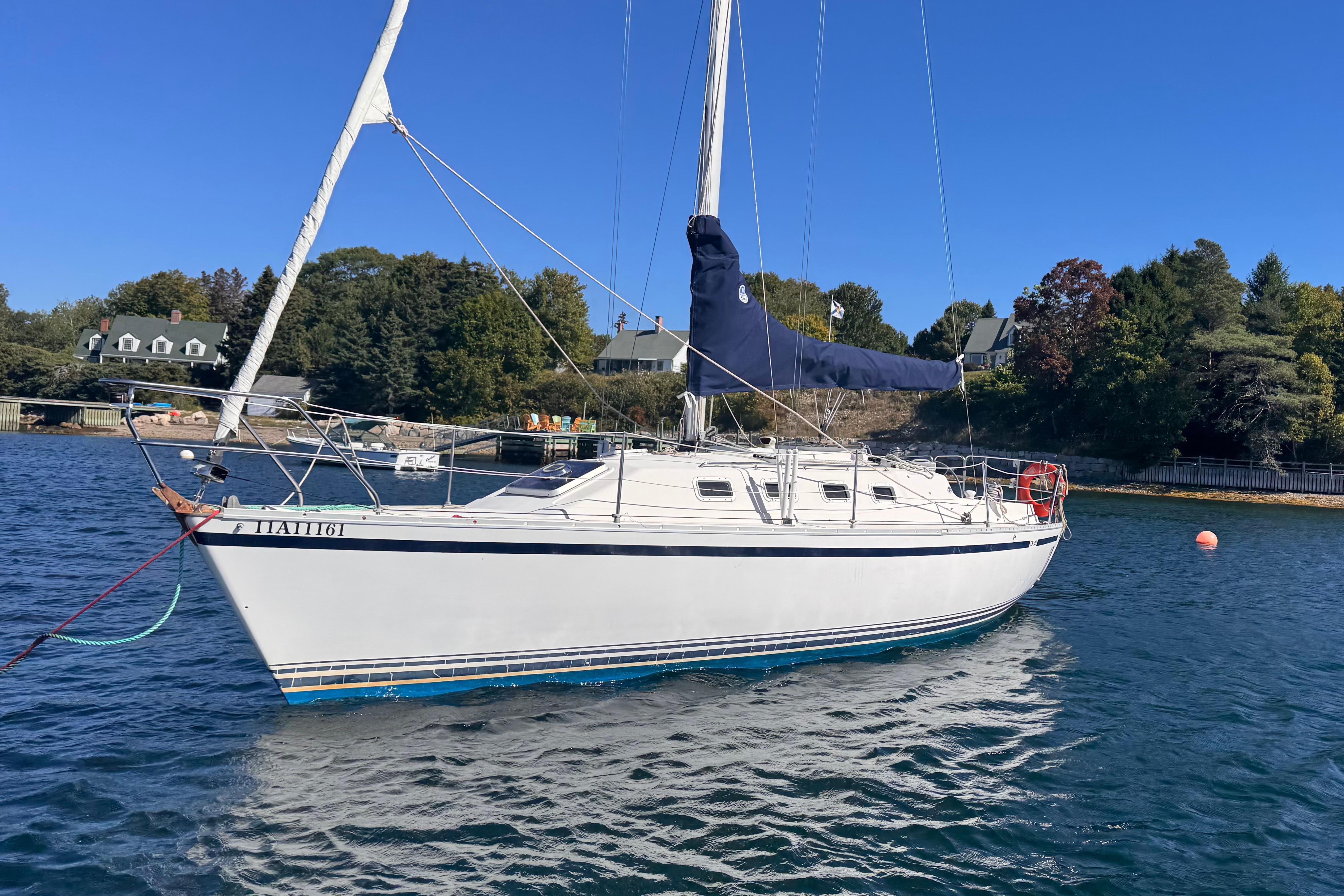 1986 CS 30 sailboat anchored in a scenic harbor with clear blue skies.