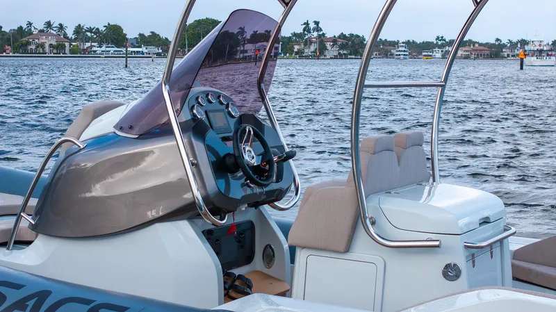  Yacht Photos Pics 2024 SACS Strider 900 boat interior with steering wheel, dashboard, and seating on a calm water backdrop.