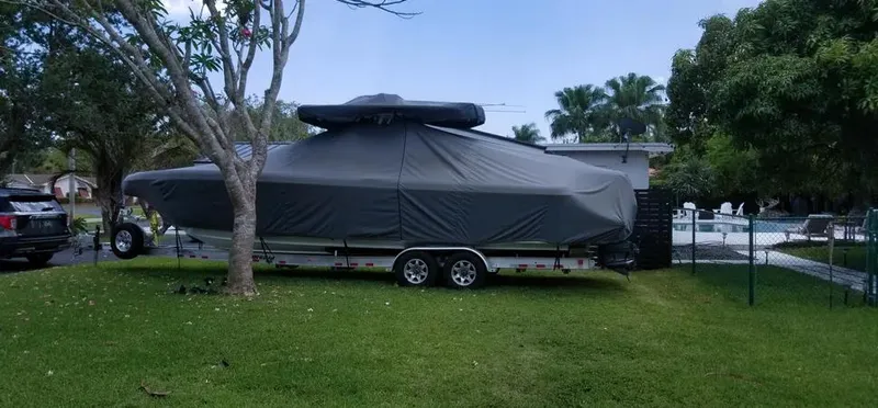  Yacht Photos Pics 2016 Intrepid 327 Center Console boat covered on a trailer in a grassy yard.