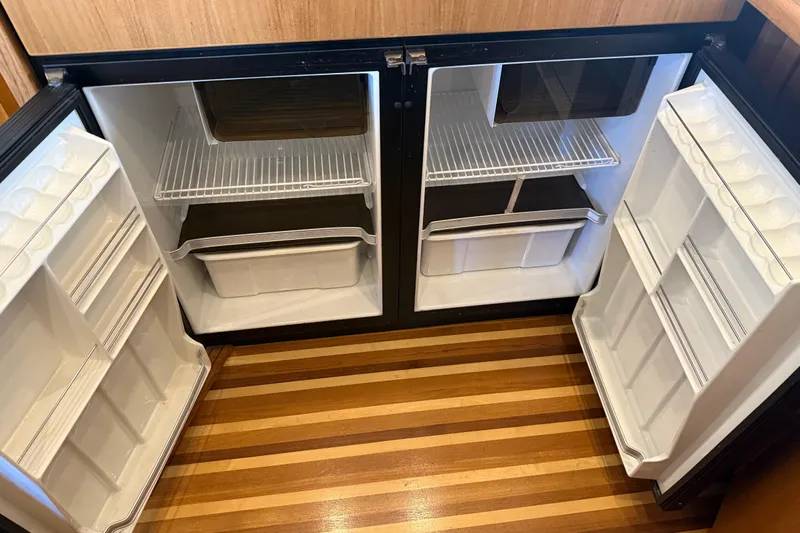 Touchdown Yacht Photos Pics Empty refrigerator in 2000 Bayliner 3988 Command Bridge Motoryacht, featuring wooden flooring.