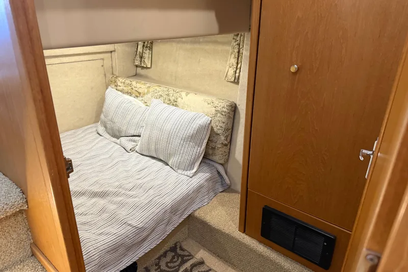 Touchdown Yacht Photos Pics Cozy bedroom in 2000 Bayliner 3988 Command Bridge Motoryacht with striped bedding and wood accents.