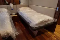Twin beds in a 2010 Aicon 85 yacht cabin with wooden flooring.