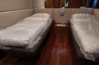 Twin beds in a luxurious 2010 Aicon 85 yacht cabin with wooden flooring.