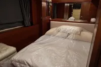 Luxurious bedroom interior of 2010 Aicon 85 yacht with elegant wood finishes and cozy bedding.