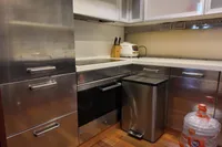 Modern kitchen with stainless steel appliances and wooden flooring, featuring a sleek design.