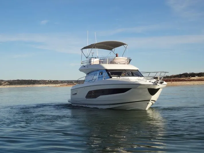 Yacht Photos Pics 2024 Prestige 420F yacht cruising on a calm lake under a clear sky.