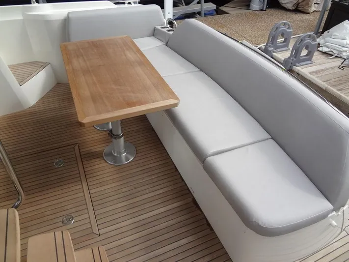  Yacht Photos Pics Prestige 420F 2024 boat deck with cushioned seating and wooden table.