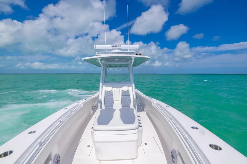  Yacht Photos Pics 2024 Invincible 33 Open Fisherman boat cruising on turquoise waters under a clear blue sky.