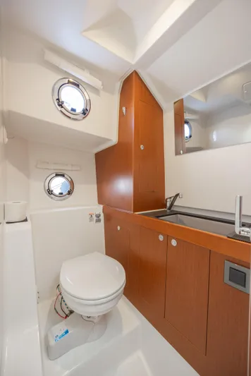 Smooth Yacht Photos Pics 2019 Beneteau Swift Trawler 30 bathroom with wooden cabinetry and porthole windows.