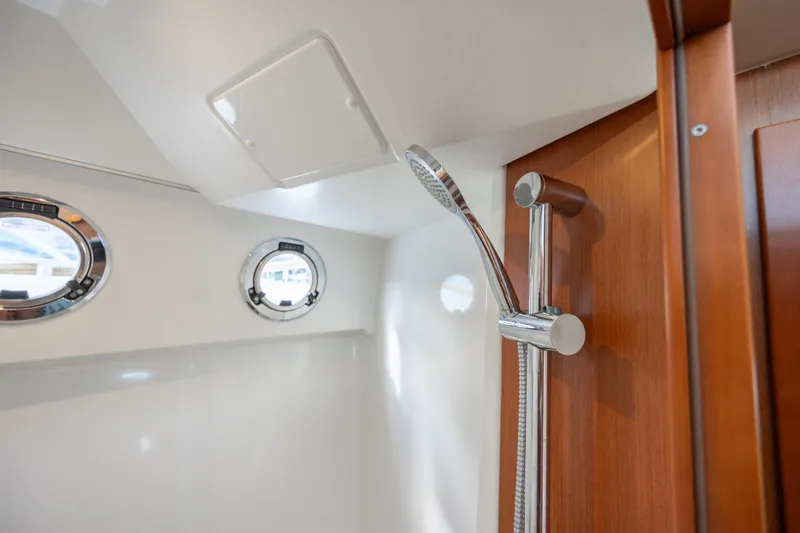 Smooth Yacht Photos Pics Interior shower area of 2019 Beneteau Swift Trawler 30 with portholes and wooden accents.