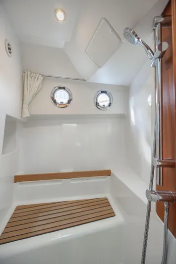 Smooth Yacht Photos Pics 2019 Beneteau Swift Trawler 30 shower with wooden bench and porthole windows.