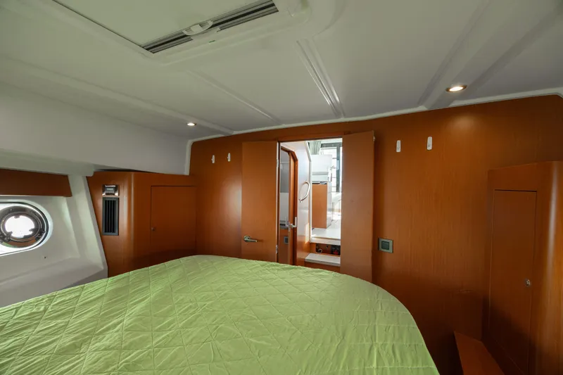 Smooth Yacht Photos Pics 2019 Beneteau Swift Trawler 30 cabin interior with green bedding and wooden finishes.
