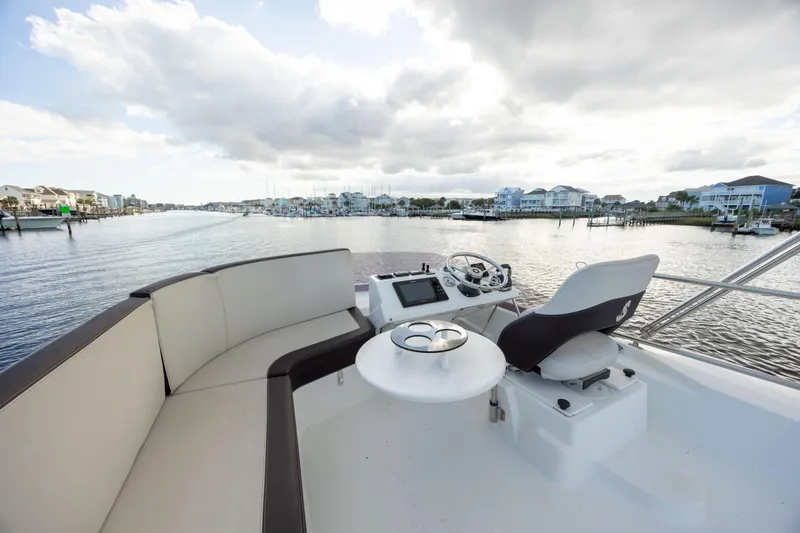 Smooth Yacht Photos Pics 2019 Beneteau Swift Trawler 30 helm with seating, overlooking a scenic waterfront.