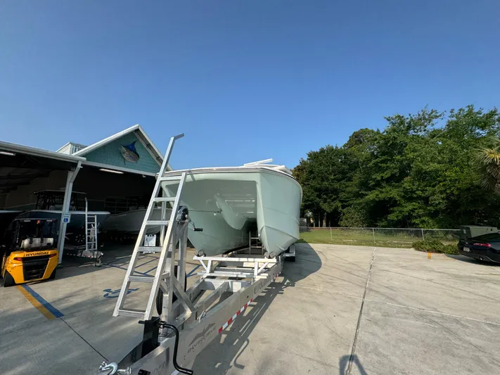  Yacht Photos Pics 2022 Invincible 40 Catamaran on trailer, parked outdoors near a building and trees.