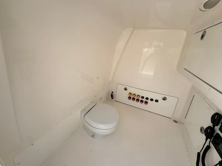  Yacht Photos Pics Interior of 2022 Invincible 40 Catamaran showing a compact marine toilet and control panel.