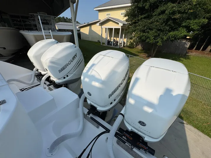  Yacht Photos Pics Four Mercury outboard engines on a 2022 Invincible 40 Catamaran, parked near a house.