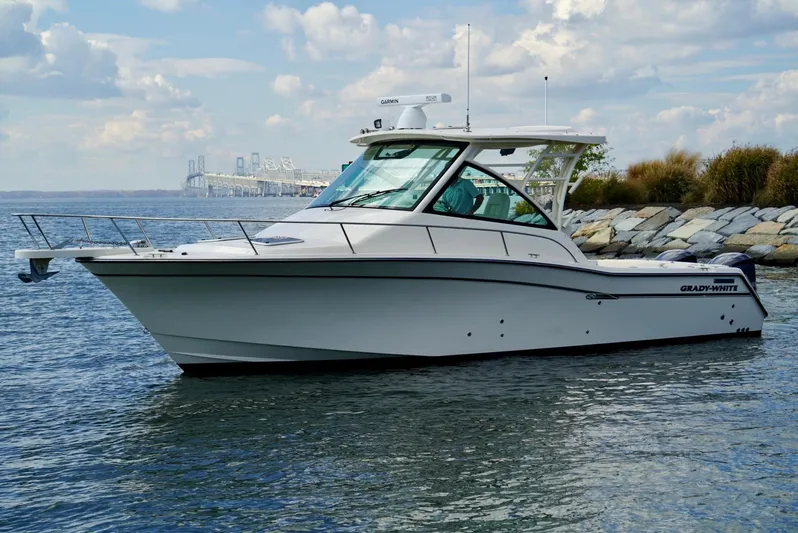  Yacht Photos Pics 2016 Grady-White Express 330 boat on calm water near rocky shoreline.