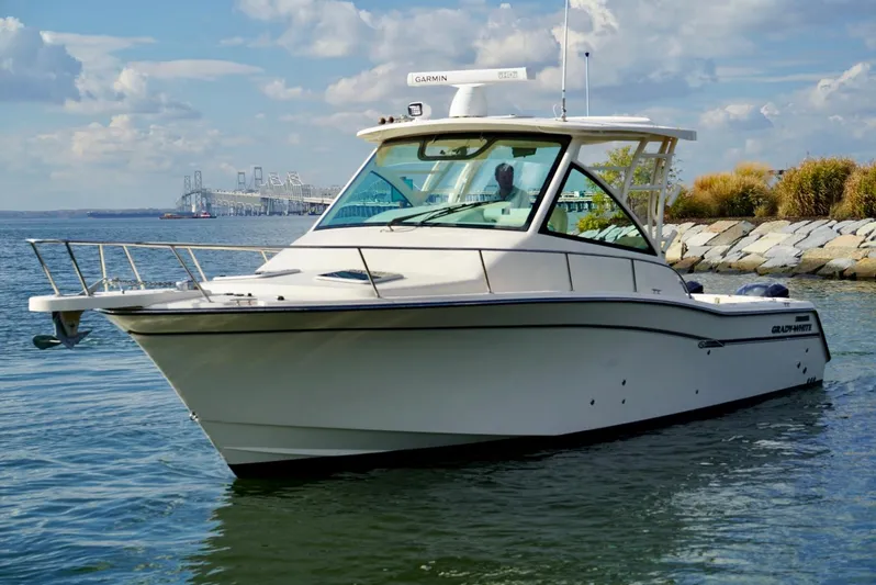  Yacht Photos Pics 2016 Grady-White Express 330 boat on calm water near rocky shoreline.