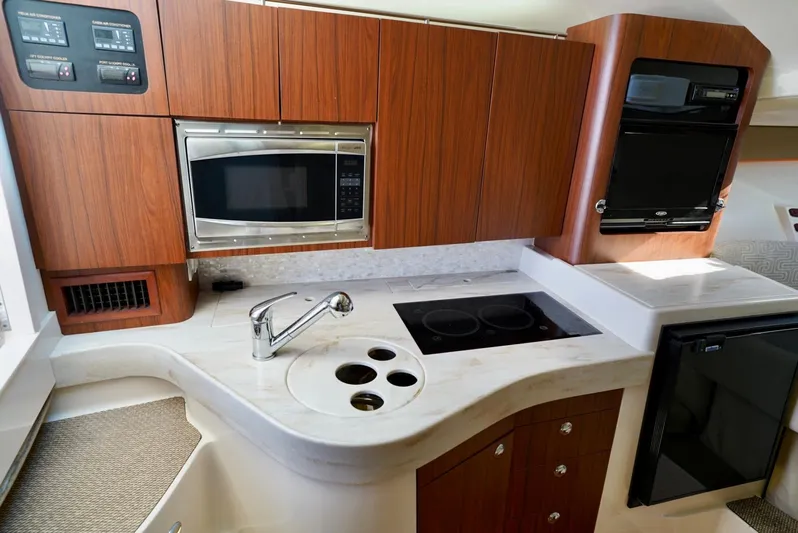  Yacht Photos Pics 2016 Grady-White Express 330 kitchen with wood cabinets, microwave, stove, and sink.