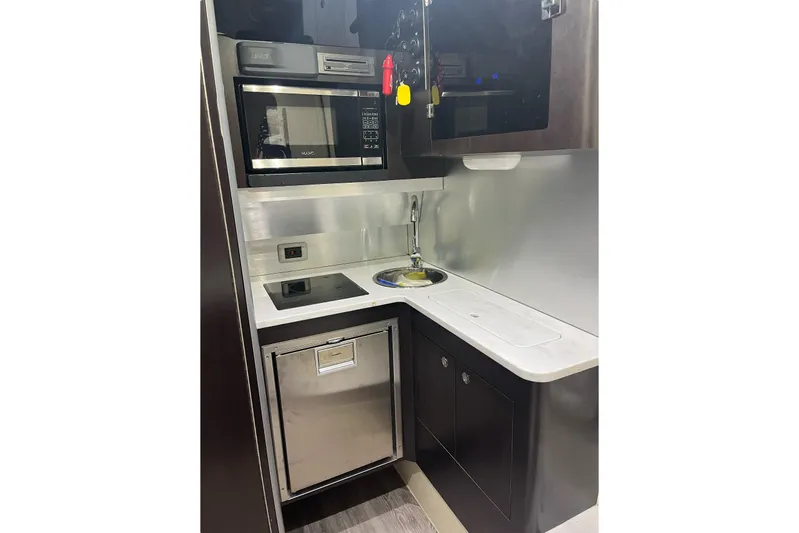  Yacht Photos Pics Compact kitchen area in a 2019 Scout 380 LXF boat, featuring modern appliances and sleek design.