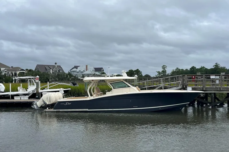  Yacht Photos Pics 2019 Scout 380 LXF boat docked by a wooden pier under cloudy skies.