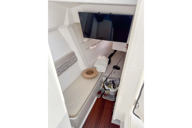  Yacht Photos Pics 2024 Pursuit DC 365 Dual Console cabin interior with seating, TV, and fishing gear.