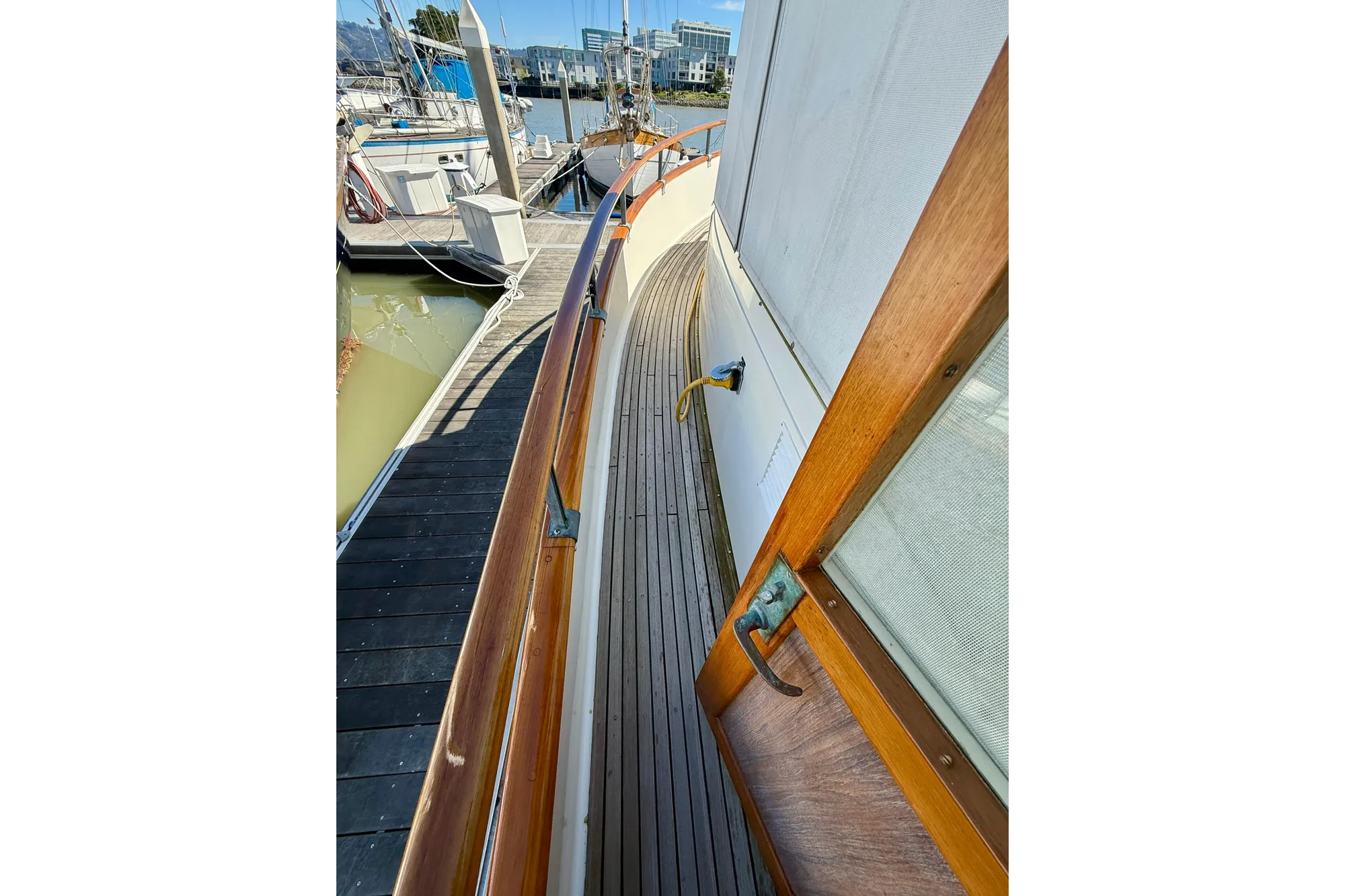 1982 Grand Banks 42 Classic yacht deck with wooden railings and marina view.