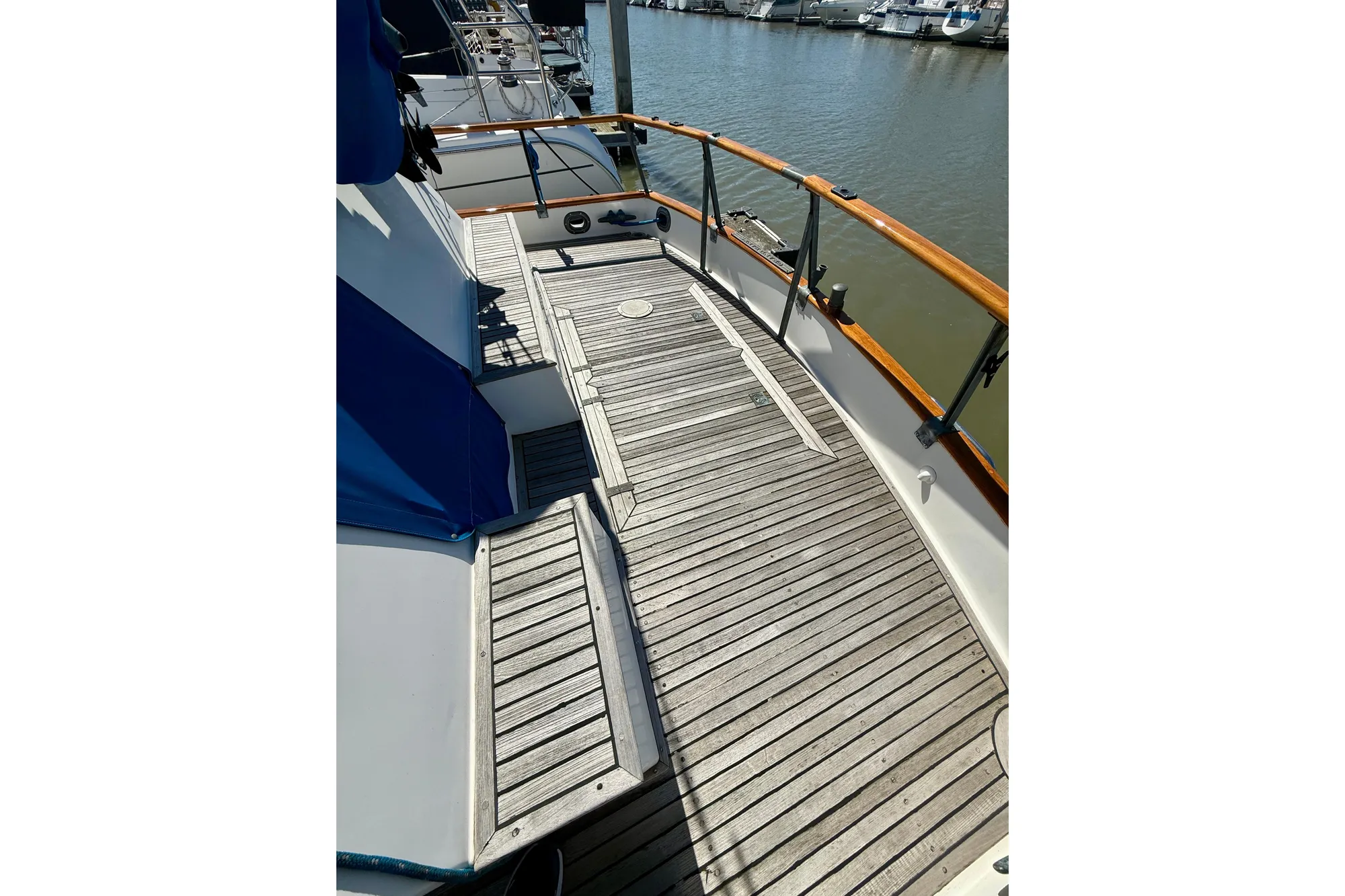 1982 Grand Banks 42 Classic yacht deck with wooden flooring and railing, docked at marina.