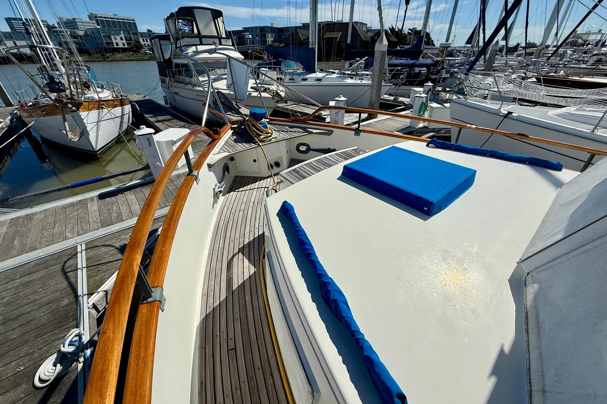 1982 Grand Banks 42 Classic yacht docked at marina, featuring wooden railings and blue cushions.