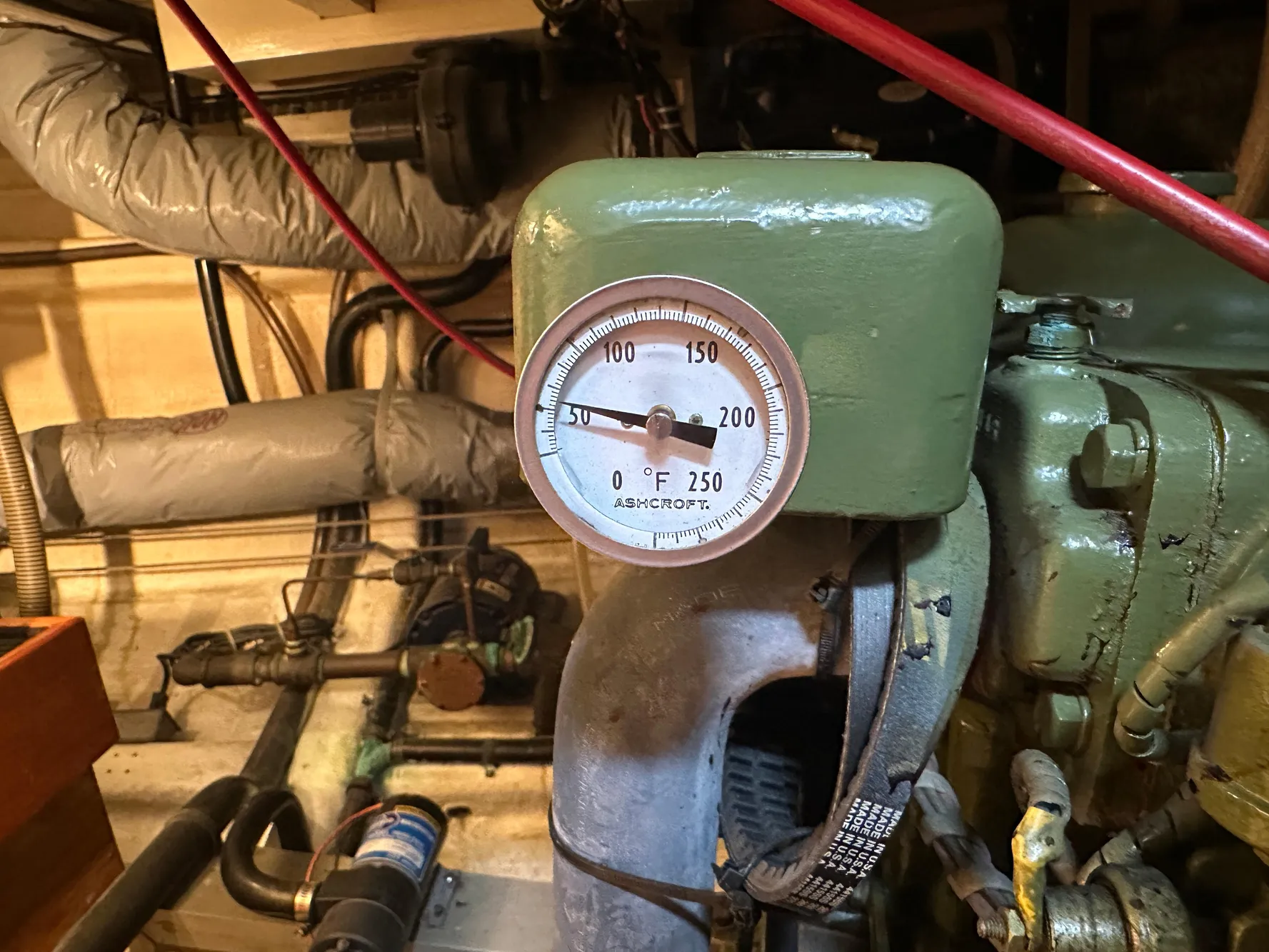 Engine room of a 1982 Grand Banks Classic with temperature gauge and pipes.