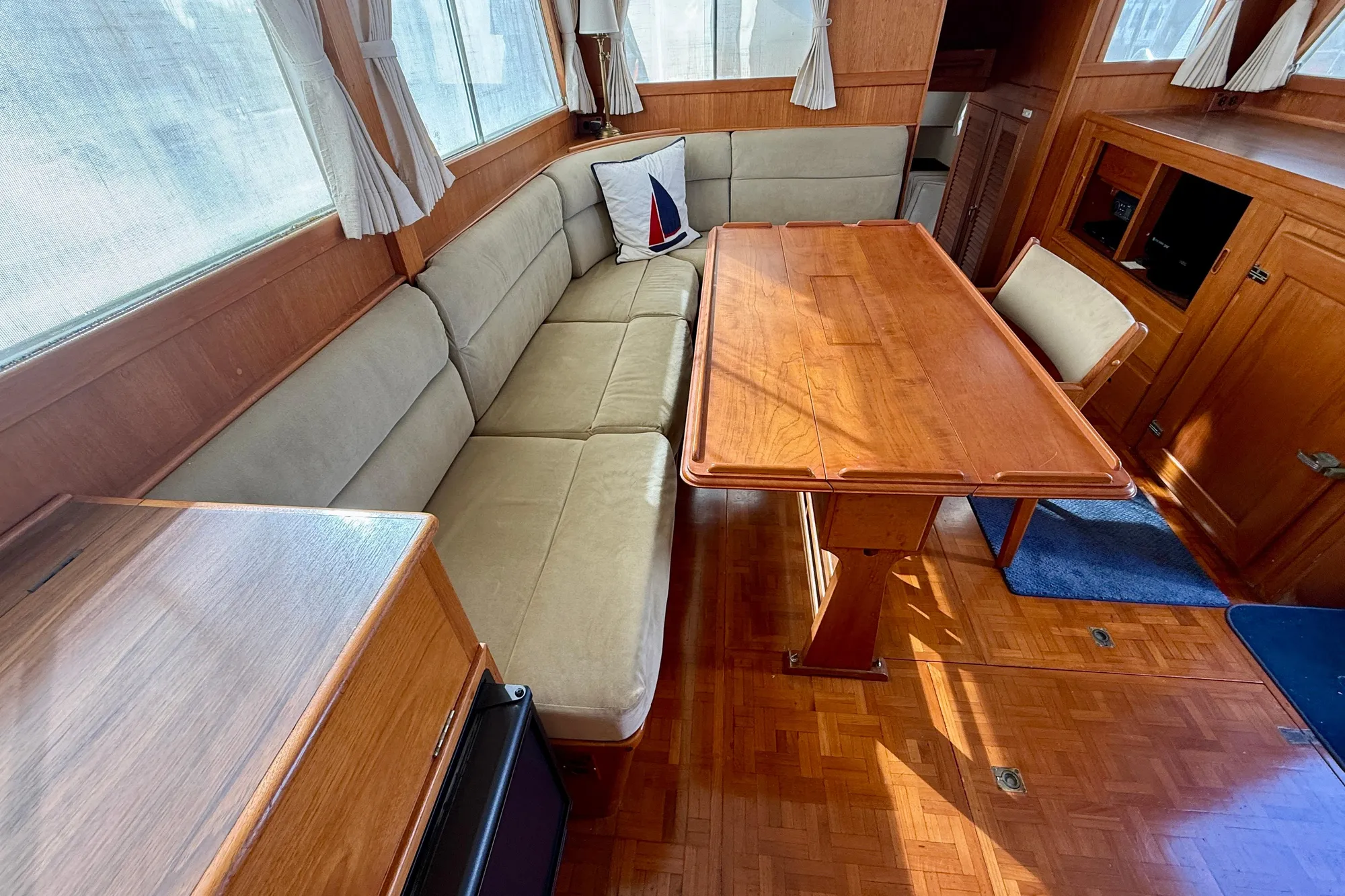 Interior of 1982 Grand Banks Classic yacht with wooden table and cushioned seating.