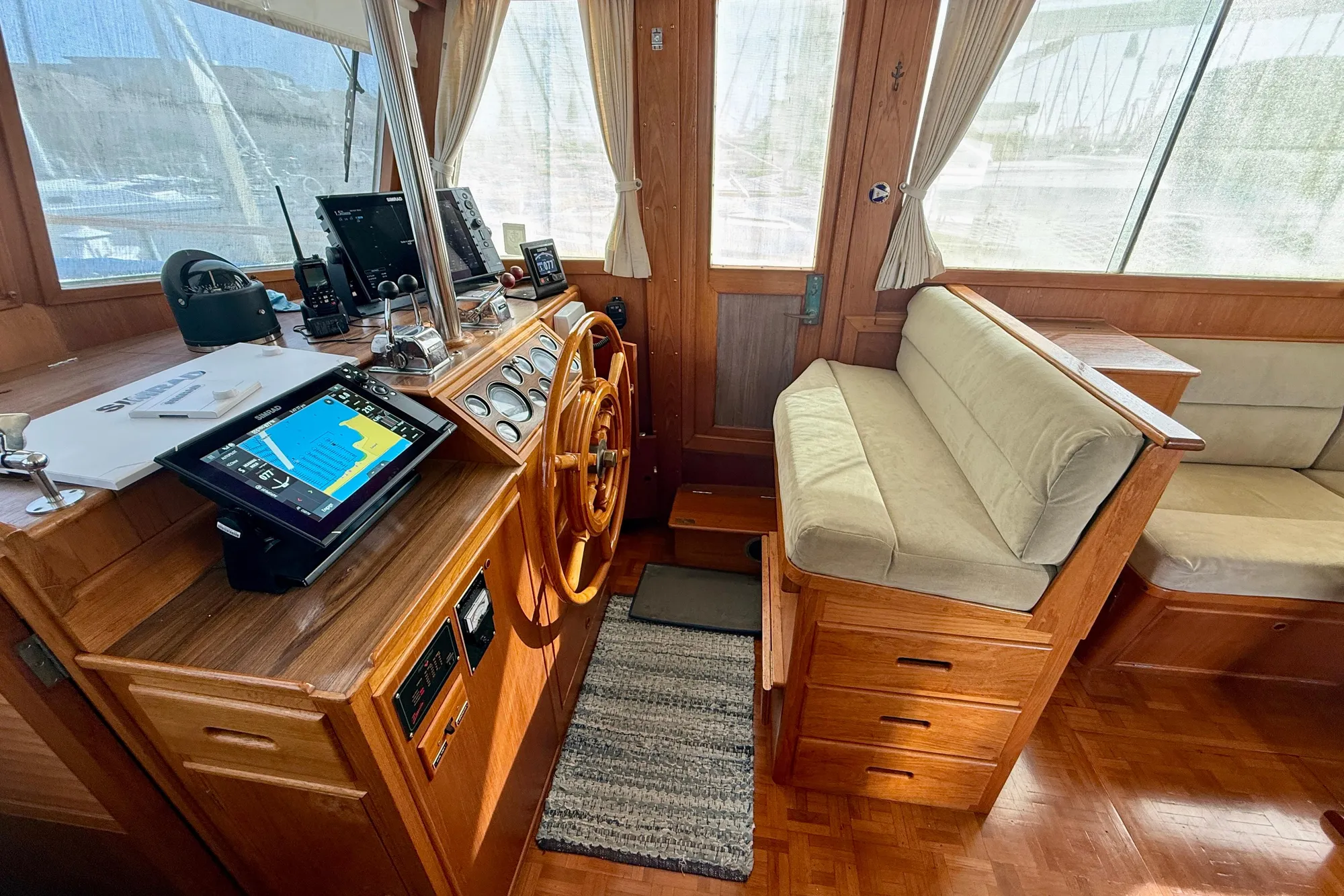 1982 Grand Banks Classic yacht interior with wooden helm, navigation equipment, and cushioned seating.