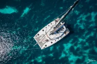 Aerial view of 2026 Nautitech 44 Open catamaran sailing on clear blue water.