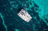Aerial view of 2025 Nautitech 44 Open catamaran on clear turquoise water.