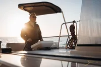 Person steering Nautitech 44 Open yacht at sunset, 2026 model.