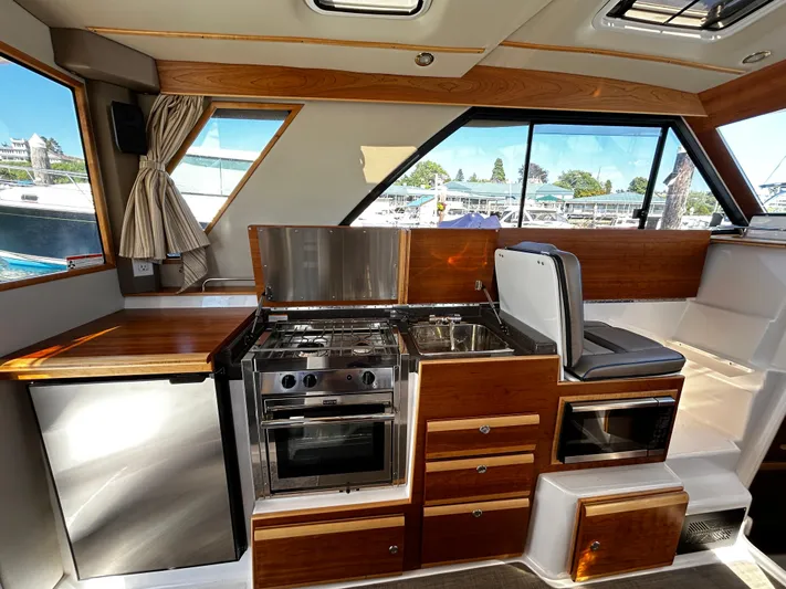 Blue Gail Yacht Photos Pics Interior of 2020 Cutwater C-30 Sedan with kitchen, stove, and seating area.